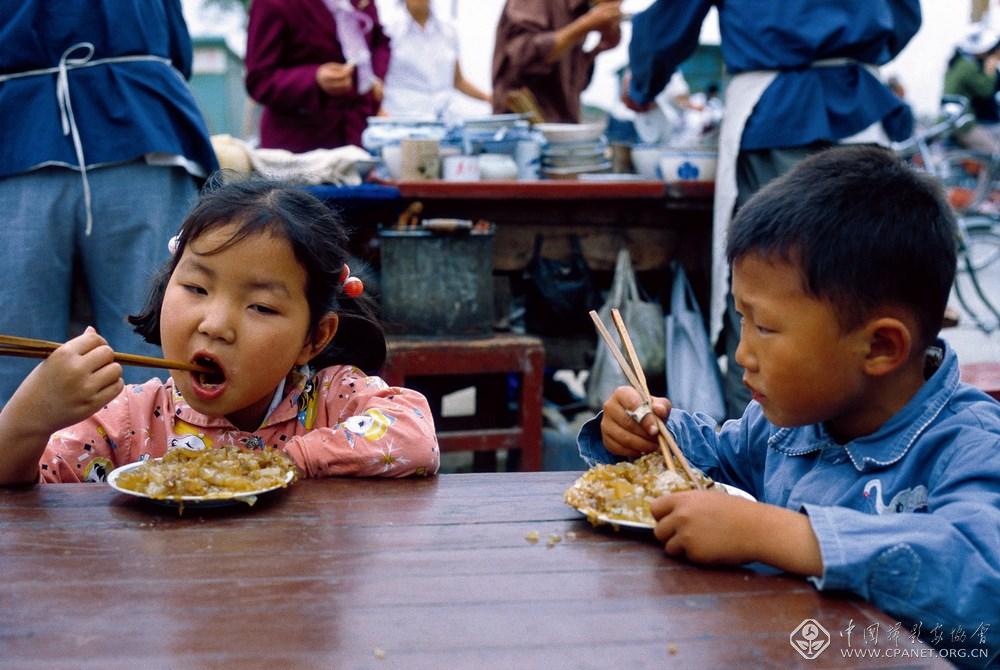 阿德里亚诺·马达罗  编号：1-08；图片说明：开封 两个小孩正在小吃摊前吃凉粉 (复制).jpg