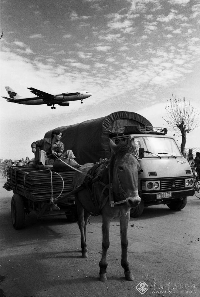吴家林-云南省新闻图片社，1998年，云南省昆明机场附近道路,这张照片，表面上是在记录交通工具：飞机，汽车，马车，自行车；实则是对当代中国一个时代现状的慨扩和缩影.jpg