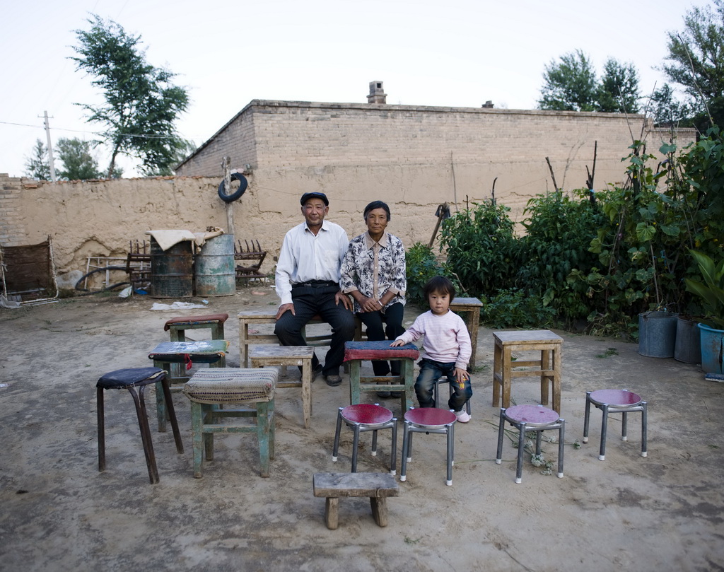 陕西省定边县堆子梁镇，67岁的薛丕忠（左）、老伴杨桂兰和孙子在自己家里（2011年8月23日摄）。薛丕忠家里有十几口人离开农村，外出打工或上学。