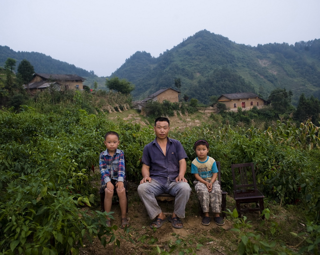 陕西省安康市双龙镇，程孝林和两个孩子在山顶的菜地里（2011年8月28日摄）。程孝林的妻子在外打工。